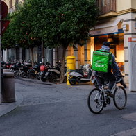 Uber Eats delivery rider cycling through a street in Spain with a green delivery backpack