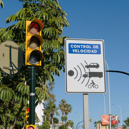 Spanish speed control sign with traffic light and Velolaser radar warning on a sunny street