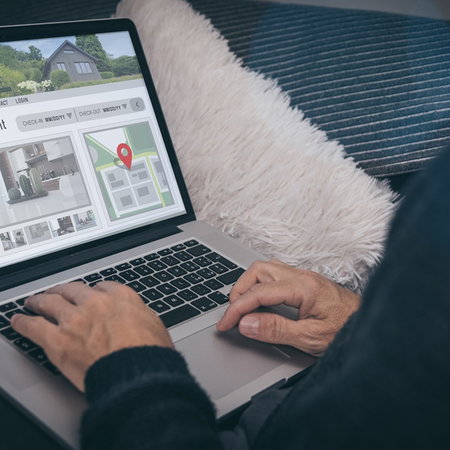 Person browsing a holiday rental listing on a laptop, checking apartment details online