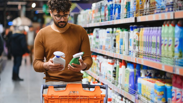 Man comparing cleaning products in a supermarket