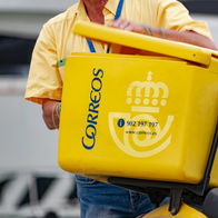Correos postal worker delivering mail with a yellow delivery box in Spain