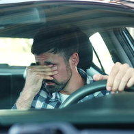 Tired driver rubbing his eyes behind the wheel due to fatigue and low energy while driving in Spain