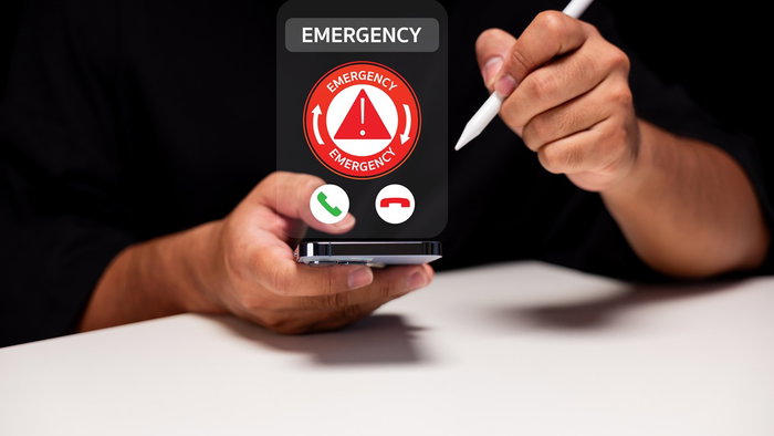 Smartphone displaying an emergency alert screen while a person holds the device.