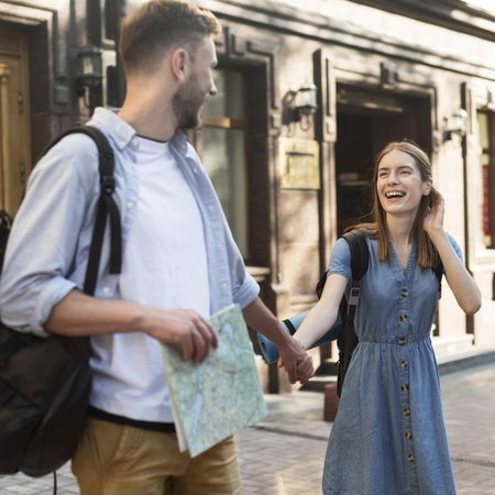 Young EU couple arriving in Spain with backpacks exploring a city street after moving