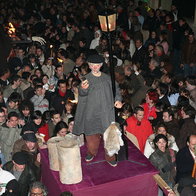 Crowd in León during the Genarín procession carrying a figure of Genarín with torches and people drinking in the streets at night