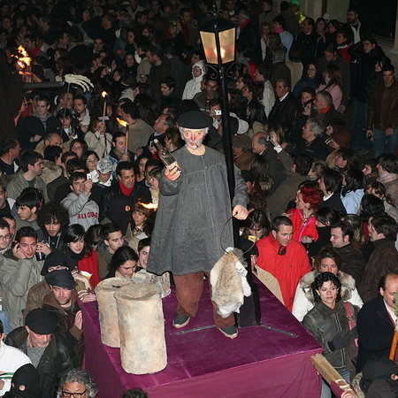 Crowd in León during the Genarín procession carrying a figure of Genarín with torches and people drinking in the streets at night