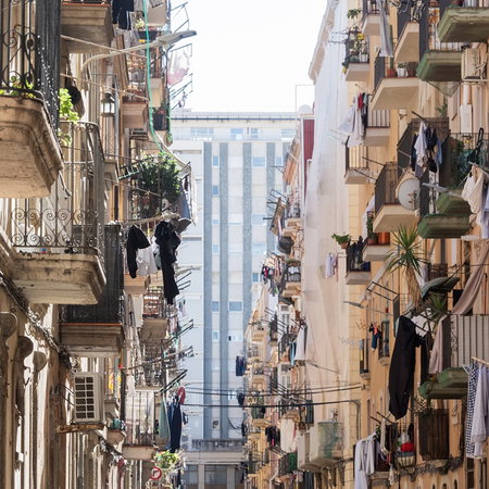 Clothes hanging from balconies in a Spanish city street, showing everyday laundry drying in urban buildings