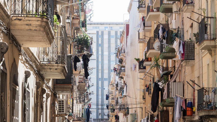 Clothes hanging from balconies in a Spanish city street, showing everyday laundry drying in urban buildings