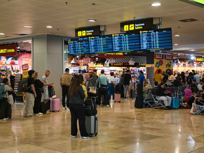 Passengers waiting with luggage in a busy Spain airport departure area during Easter travel disruption