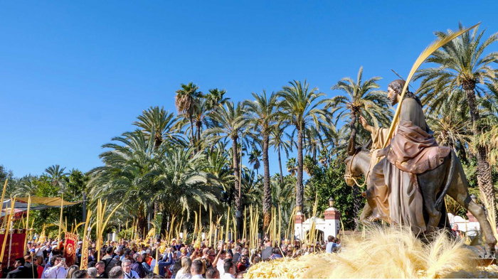 Crowd with white palm leaves during Palm Sunday procession in Elche