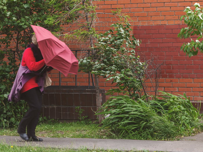 People struggling to walk through strong winds on a Spanish city street during weather alert