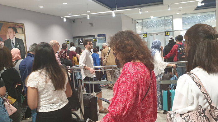 Travellers waiting in a crowded passport control queue at a Spanish airport terminal