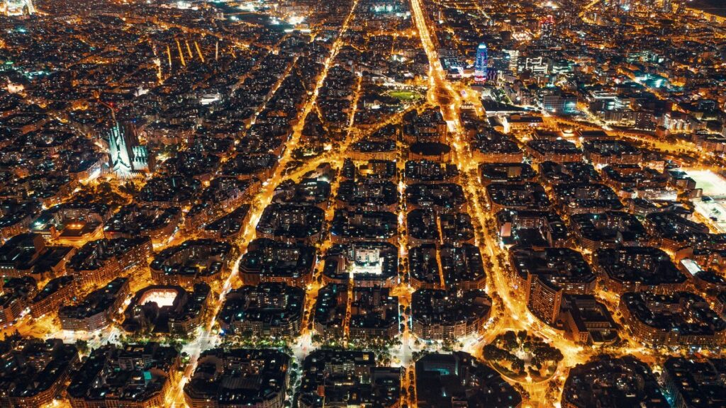 High-voltage electricity pylons carrying power above a city at night in Spain