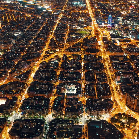 High-voltage electricity pylons carrying power above a city at night in Spain