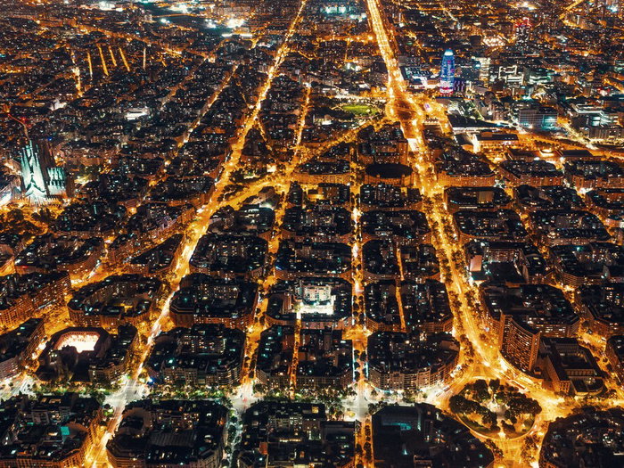 High-voltage electricity pylons carrying power above a city at night in Spain