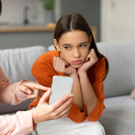 Parent showing smartphone to child while discussing messaging use
