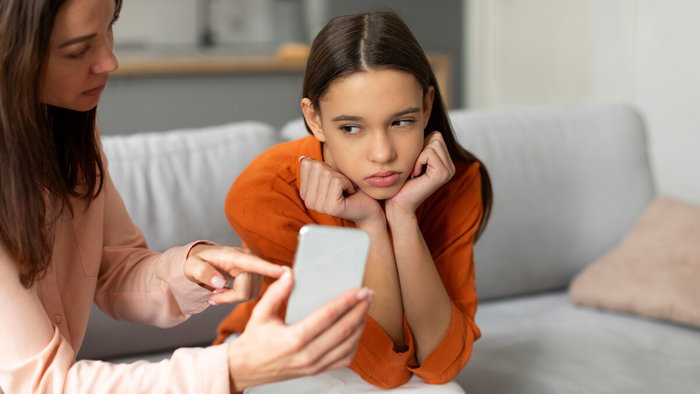 Parent showing smartphone to child while discussing messaging use