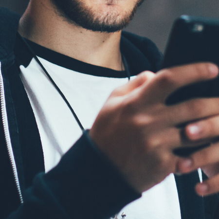 Person listening to audio on smartphone as Spain removes extremist content online