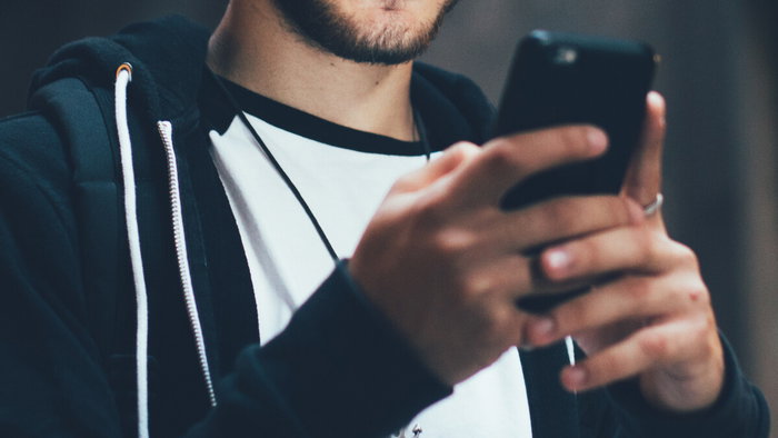 Person listening to audio on smartphone as Spain removes extremist content online