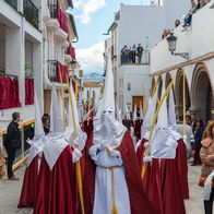 Semana Santa procession in Spain with participants in traditional robes walking through a street