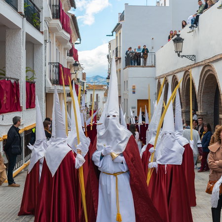 Semana Santa procession in Spain with participants in traditional robes walking through a street