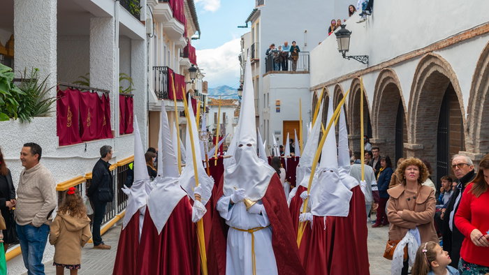 Semana Santa procession in Spain with participants in traditional robes walking through a street