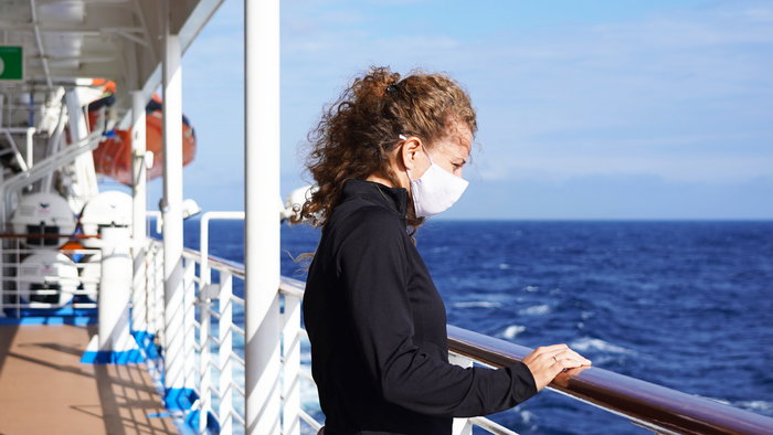 Girl on a cruise, wearing a mask.