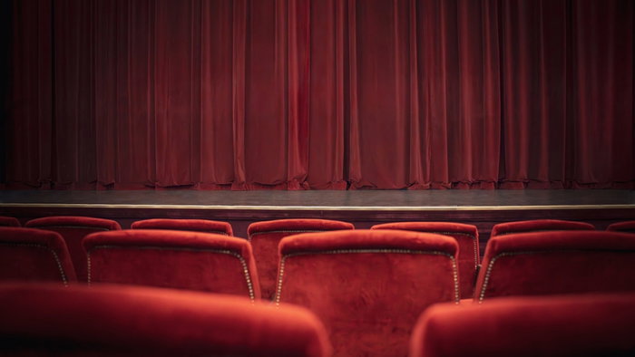 Empty red chairs and curtains in theatre.