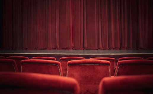Empty red chairs and curtains in theatre.