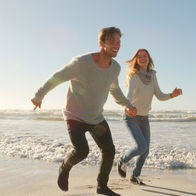Two happy people running along the beach