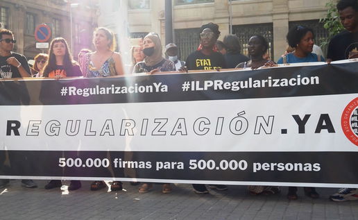 Protest in Spain calling for migrant regularisation with banner reading “Regularización Ya”