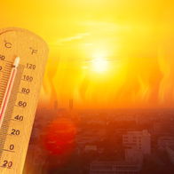 Extreme heatwave over a city with high temperatures on a thermometer under intense sun