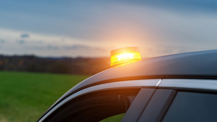 V16 emergency warning light flashing on top of a car stopped on the roadside in Spain.