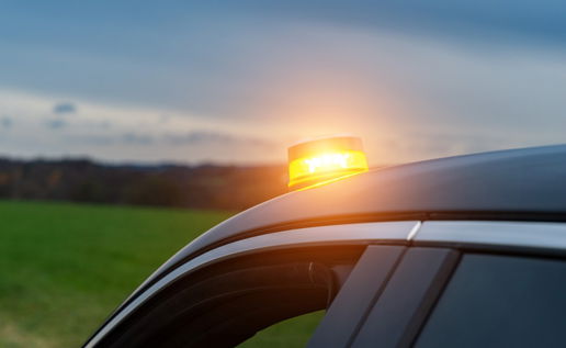 V16 emergency warning light flashing on top of a car stopped on the roadside in Spain.