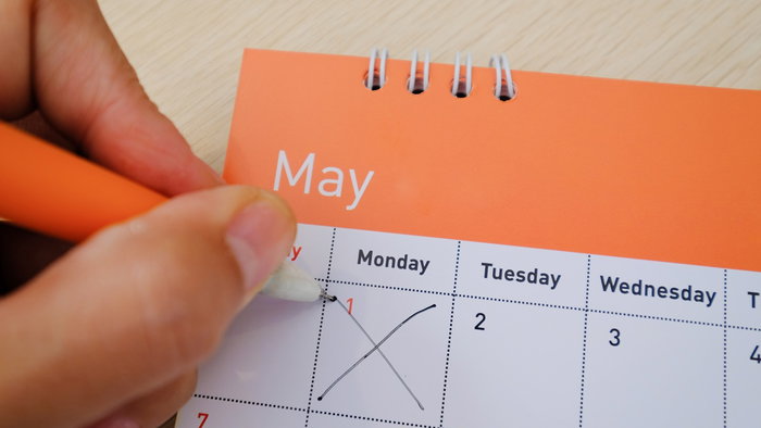 Hand marking 1 May on a calendar to highlight Spain public holiday dates