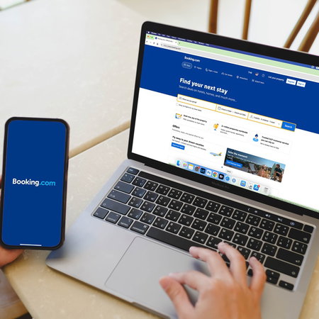 Person using Booking website on laptop and smartphone