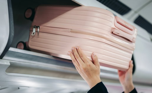 Person putting their carry-on bag in the overhead locker on an airplance