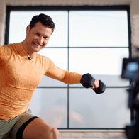 Happy fitness instructor doing a class via online video