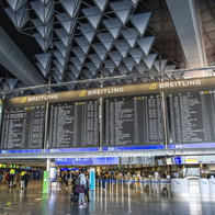 Airport departures board showing flight schedules in a busy terminal