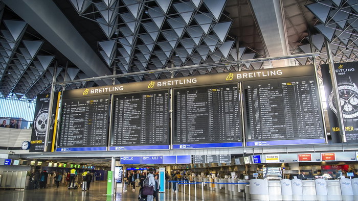 Airport departures board showing flight schedules in a busy terminal