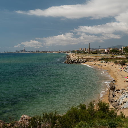 Eroded beach in Montgat near Barcelona with rocks exposed and a narrow strip of sand