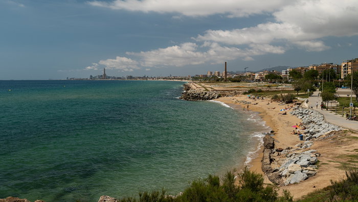 Eroded beach in Montgat near Barcelona with rocks exposed and a narrow strip of sand