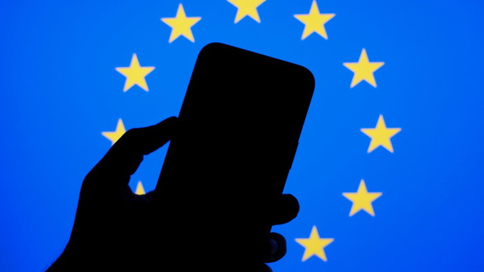 Smartphone silhouette in front of European Union flag representing new EU phone rules