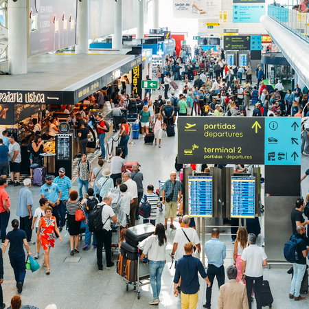 Busy airport terminal in Portugal with long queues of passengers during peak travel period