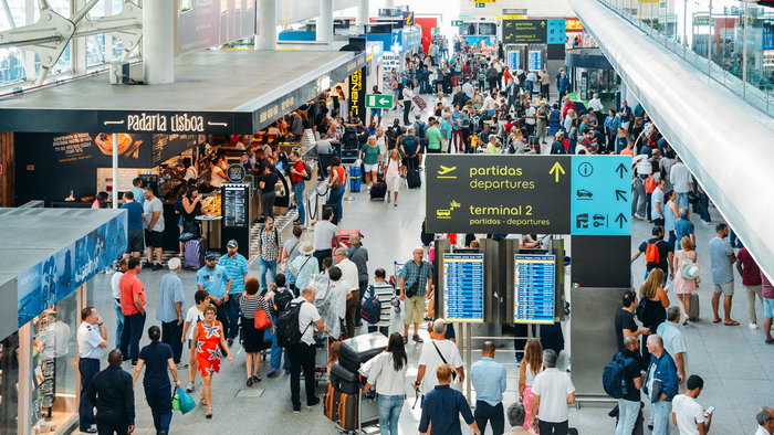Busy airport terminal in Portugal with long queues of passengers during peak travel period