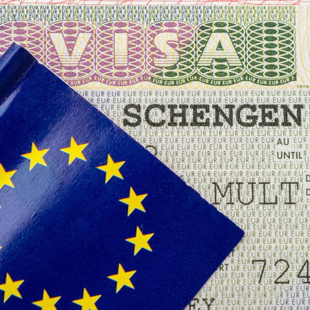 Schengen visa sticker inside a passport with EU flag cover visible