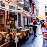 Waiter showing the menus to a couple of tourists in Malaga, Spain