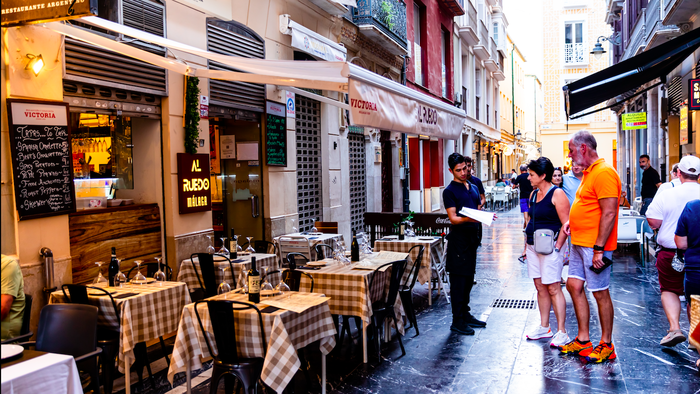 Waiter showing the menus to a couple of tourists in Malaga, Spain