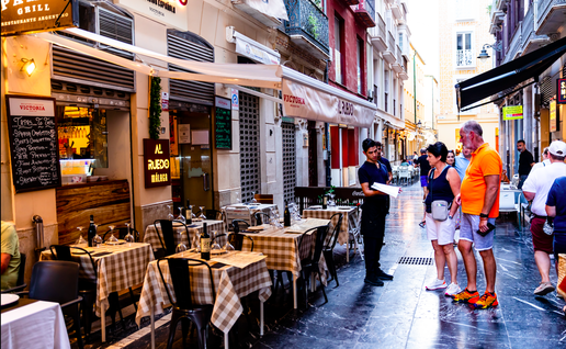 Waiter showing the menus to a couple of tourists in Malaga, Spain