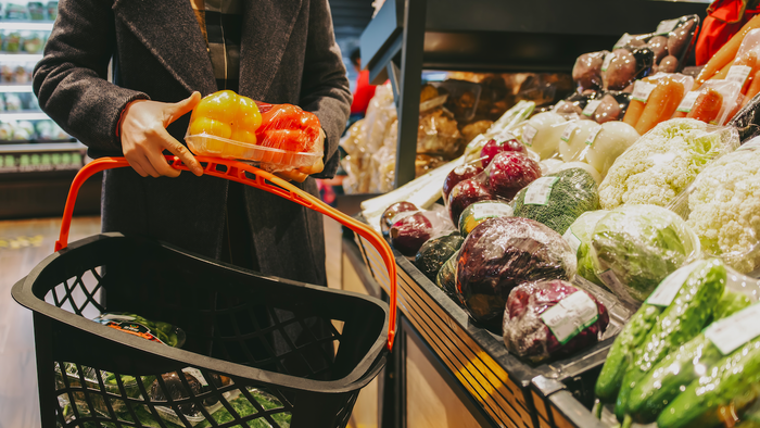 Woman holding a shopping basket holding a vegetable